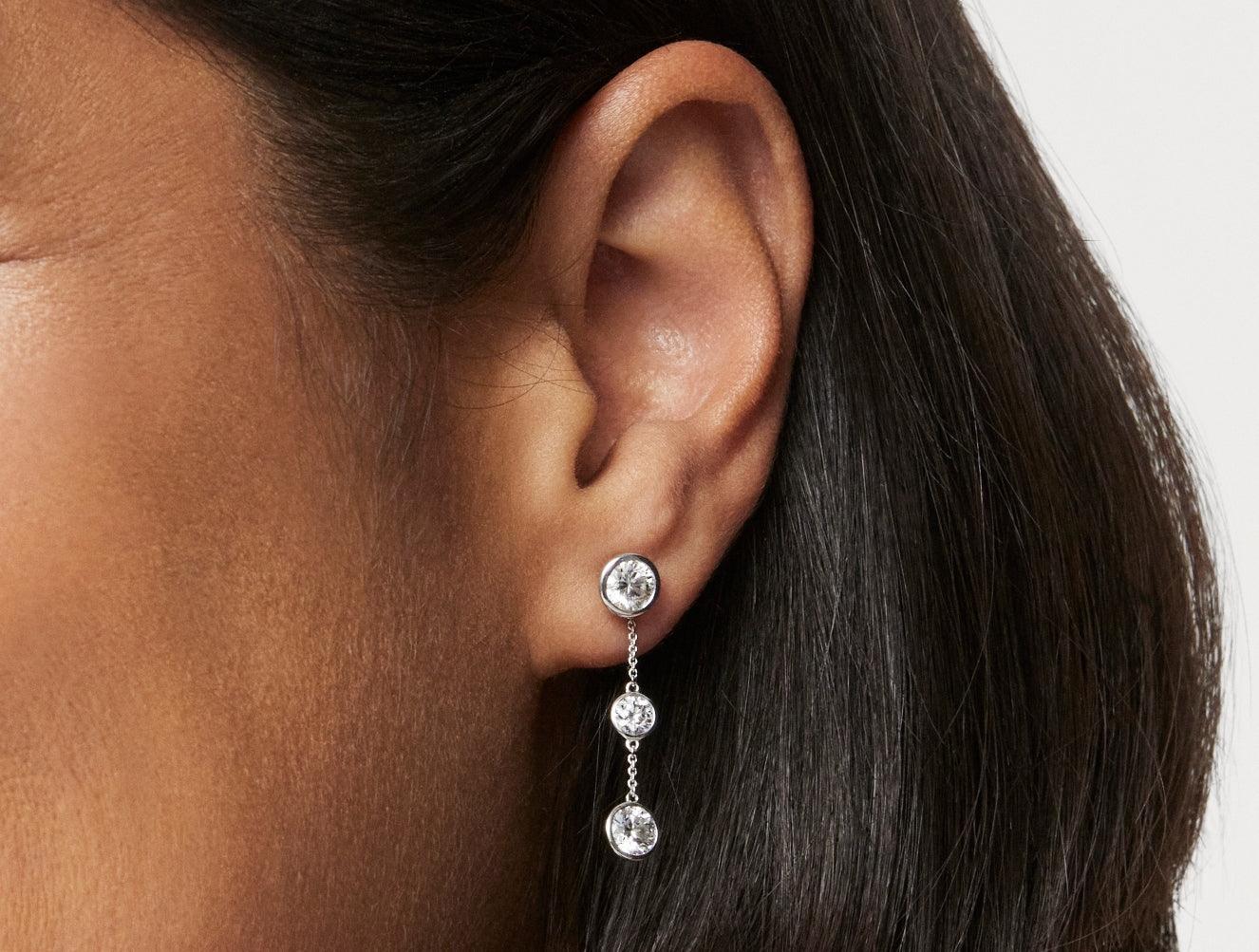 Close up model shot of 1.5 carat double round brilliant bezel drop earring jacket in 14k white gold with 0.5 carat round brilliant bezel stud