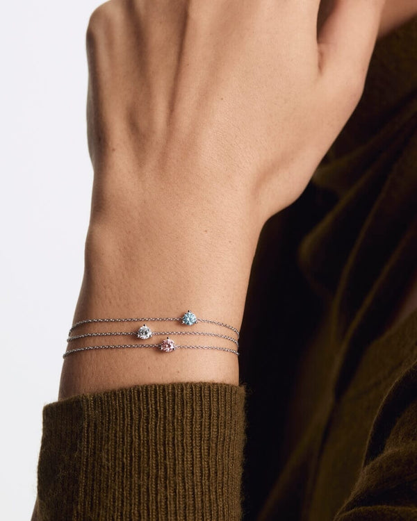 White, pink and blue mini solitaire bracelets layered on model's wrist