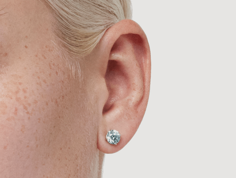Close up model shot of Lightbox Finest™ 2 carat total weight blue round brilliant solitaire studs in 18k white gold