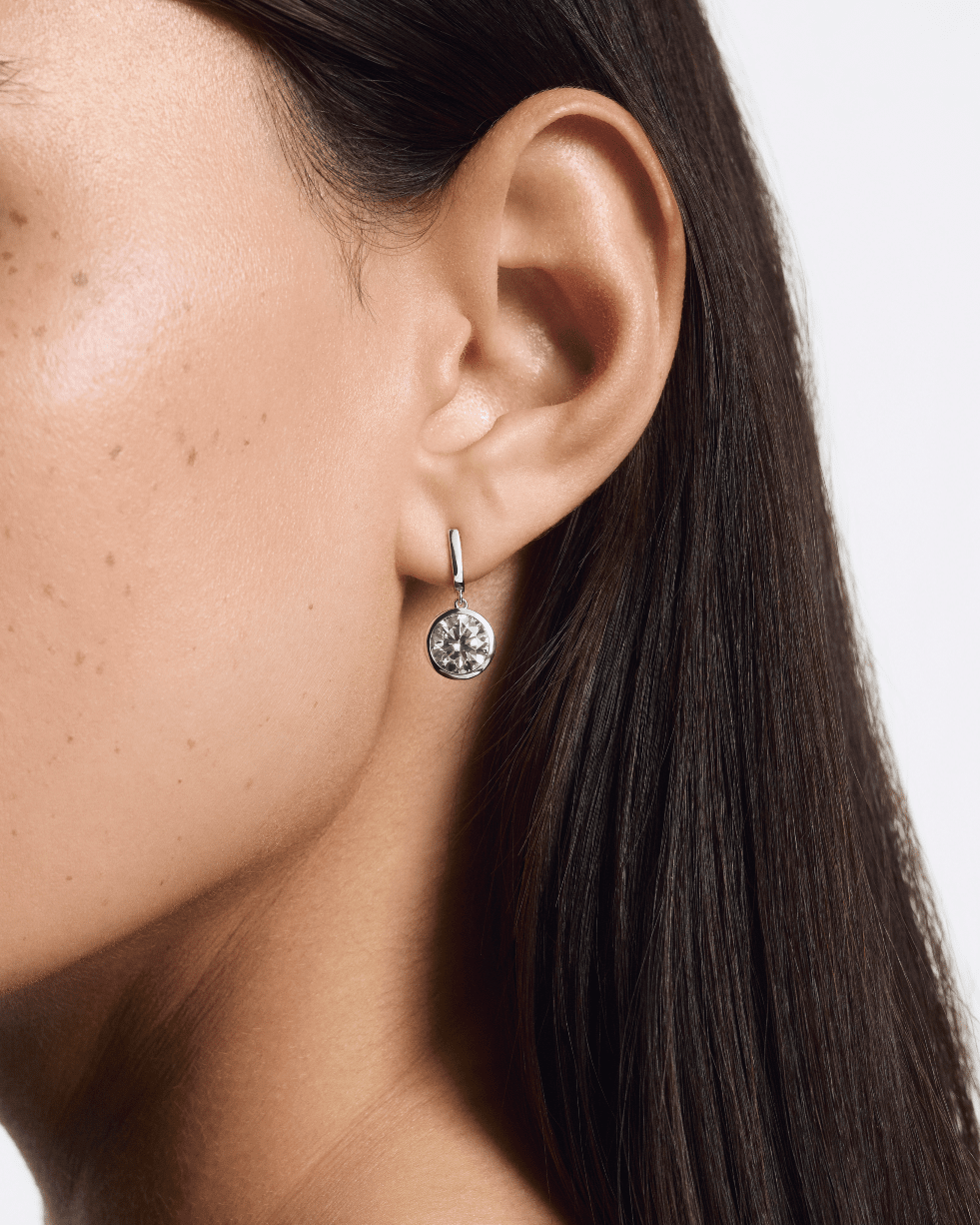 Model image of round brilliant bezel drop earrings in white gold