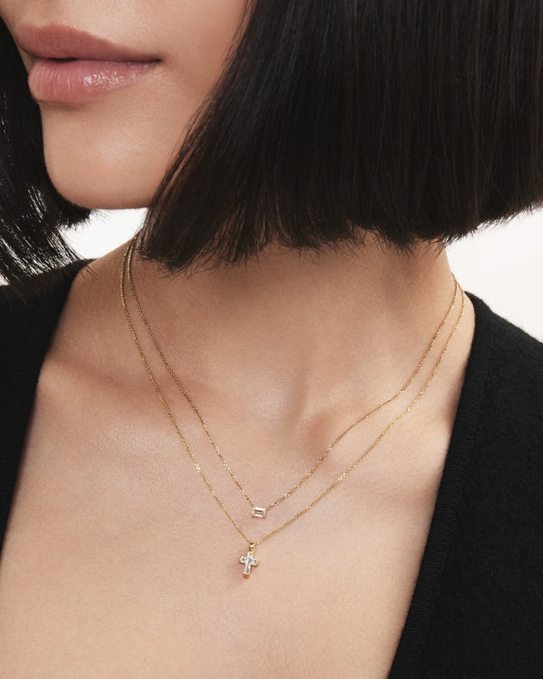 Image of model wearing the yellow gold cross cut pendant layered with the yellow gold mini baguette cut pendant