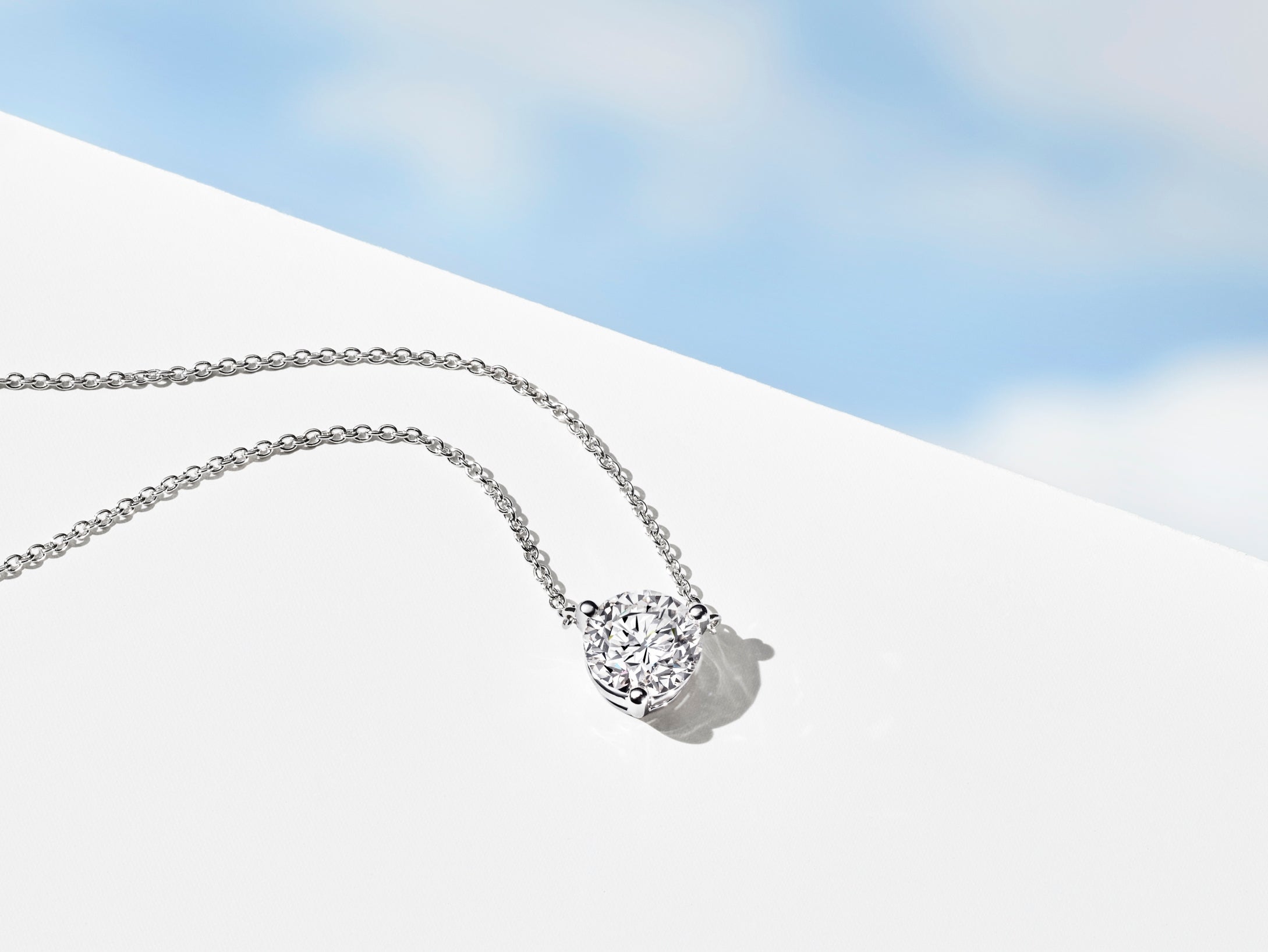 Lab-grown diamond white round brilliant pendant on blue sky 