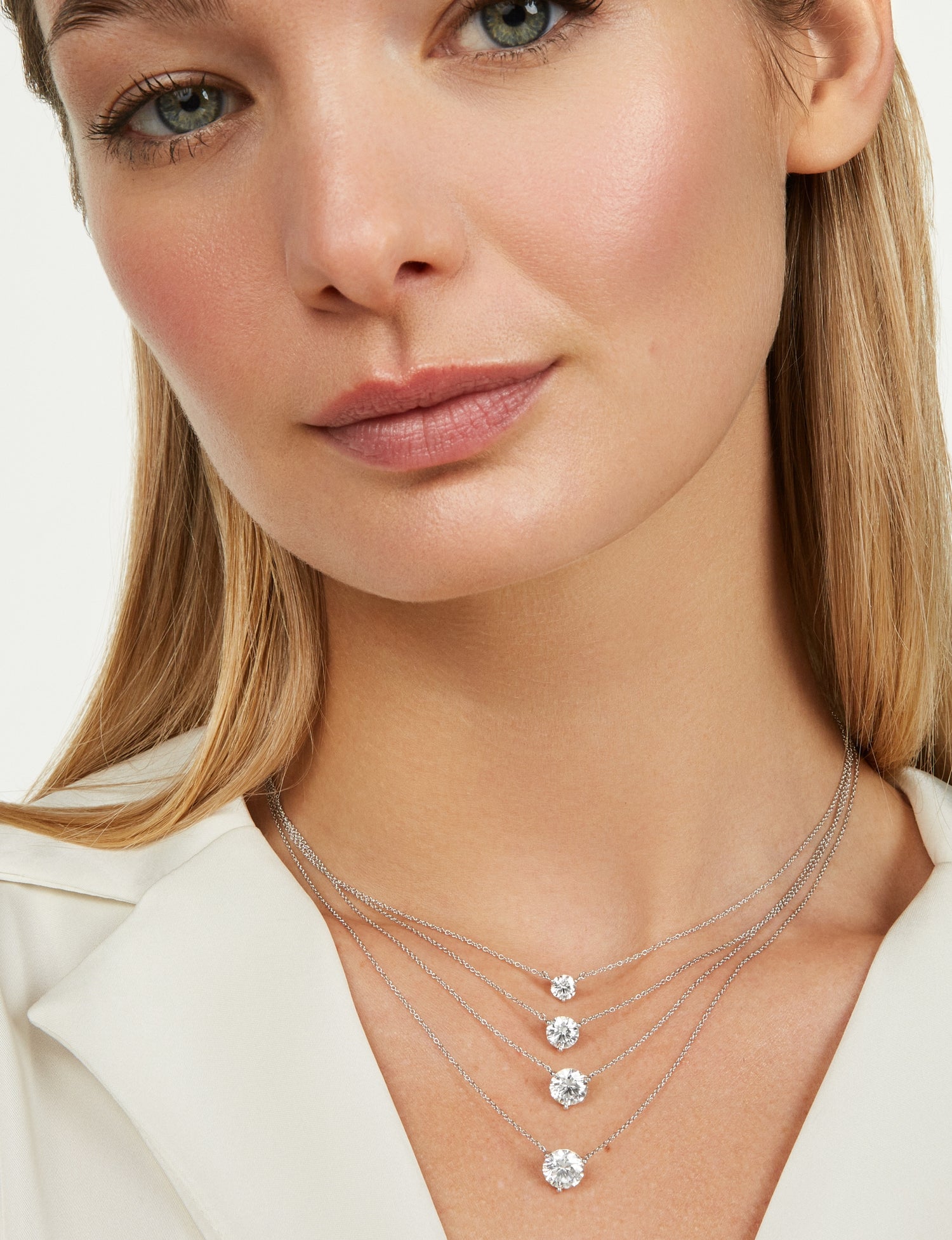 Woman wearing layered white round brilliant lab-grown diamond necklaces for carat size comparison 