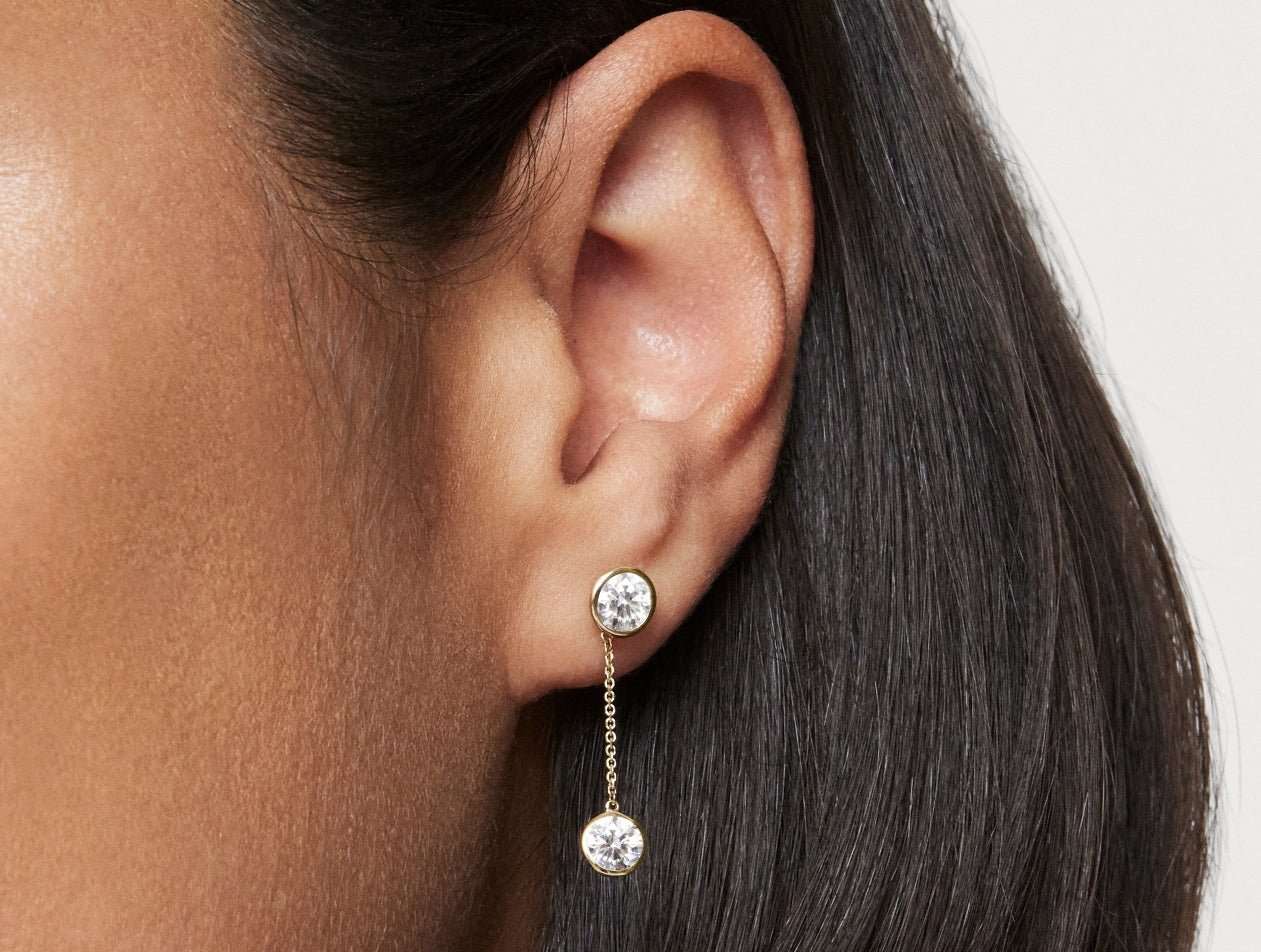 Close up model shot of 1 carat total weight round brilliant drop bezel earring jacket in 14k yellow gold with a 0.5 carat bezel round brilliant stud