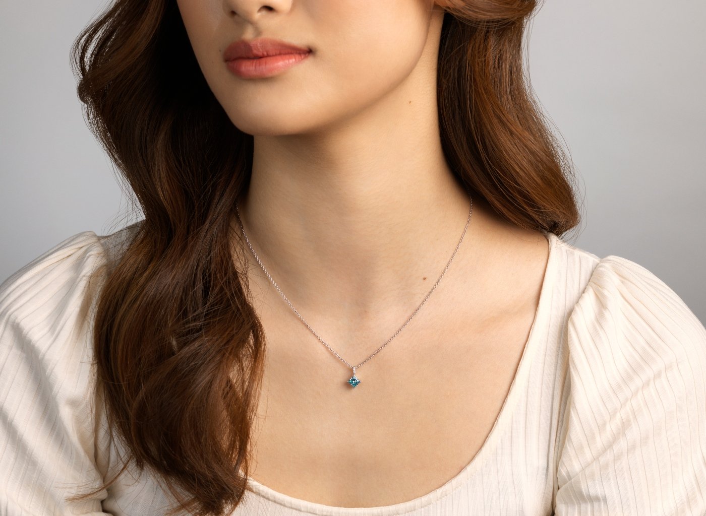Model shot of 1 carat blue lab-grown diamond princess cut pendant on a pave bale